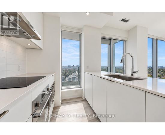 A modern kitchen with white cabinets and a large window overlooking the city.