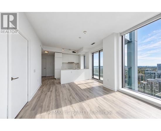 A spacious, well-lit room with wooden floors and large windows overlooking a cityscape.