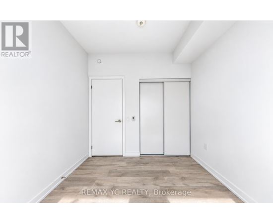 A white bedroom with two doors and a wooden floor.