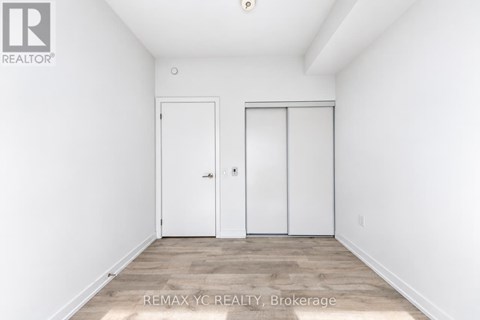 A white bedroom with two doors and a wooden floor.