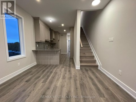 A spacious room with wooden flooring and a staircase leading to another level.