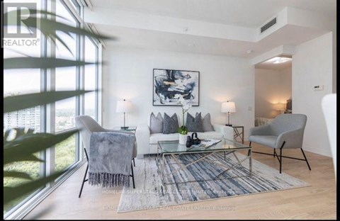 A living room with a couch, chairs, and a rug.