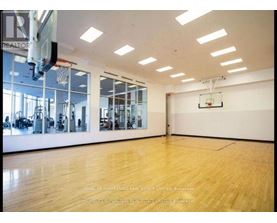 A spacious gym with wooden floors and a basketball hoop.