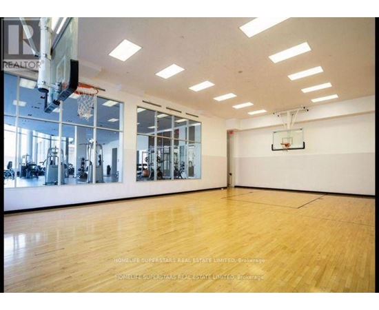 A spacious gym with wooden floors and a basketball hoop.