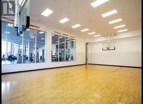 A spacious gym with wooden floors and a basketball hoop.