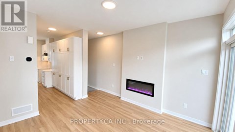 A well-lit, spacious living room with a fireplace and a realtor logo.