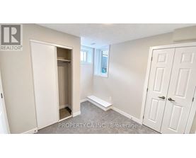 A brokerage sign is on the wall of a white bedroom.