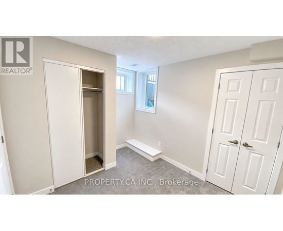 A brokerage sign is on the wall of a white bedroom.