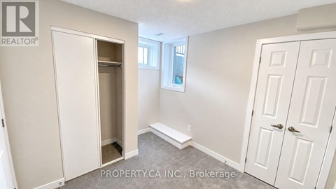 A brokerage sign is on the wall of a white bedroom.