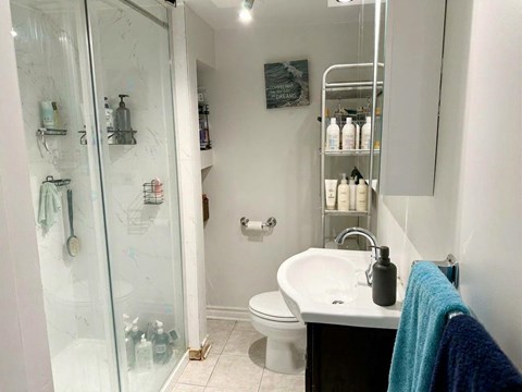 A bathroom with a white sink, toilet, and a glass shower door.