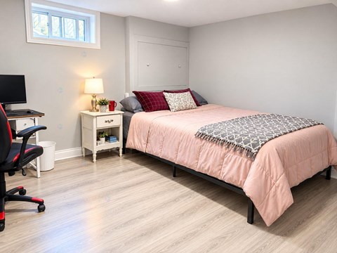 A bedroom with a bed, desk, and chair.