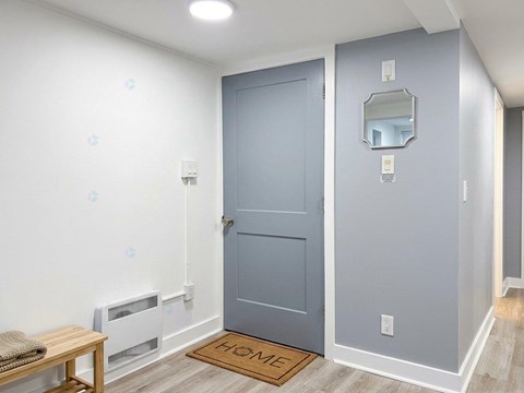 A grey door is in a room with a mirror above it.