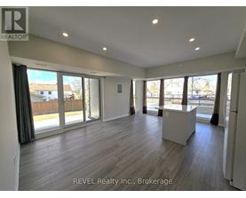 A spacious room with wooden flooring and large windows.