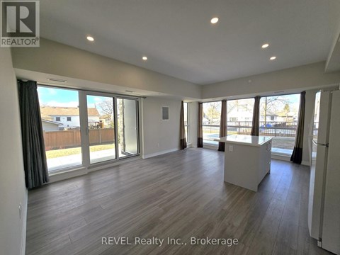 A spacious room with wooden flooring and large windows.