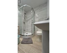 A bathroom with a white sink, a round mirror, and a glass shower stall.