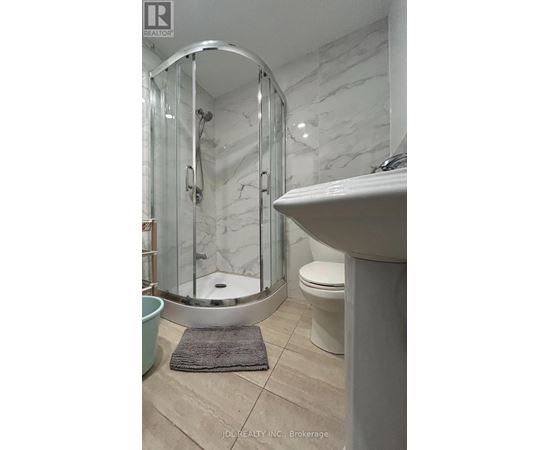 A bathroom with a white sink, a round mirror, and a glass shower stall.