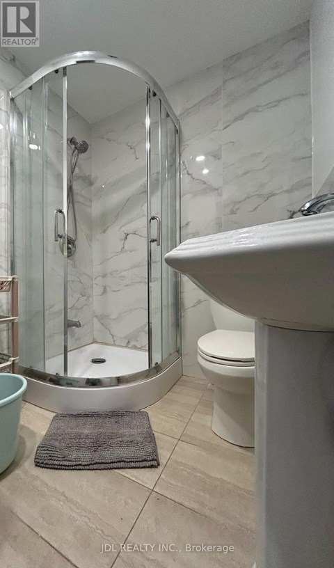 A bathroom with a white sink, a round mirror, and a glass shower stall.