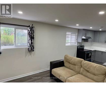 A living room with a beige couch and a black chair.