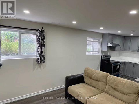 A living room with a beige couch and a black chair.
