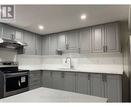 A kitchen with grey cabinets and a white countertop.
