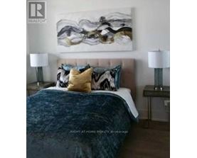 A bedroom with a large bed and a painting on the wall.
