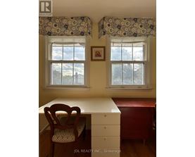 A room with a desk and chair in front of a window.