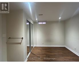 A room with wooden floors and white walls, with a door leading to another room.