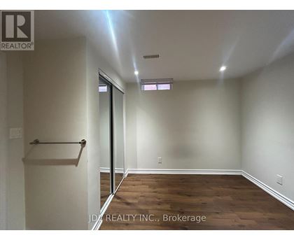 A room with wooden floors and white walls, with a door leading to another room.