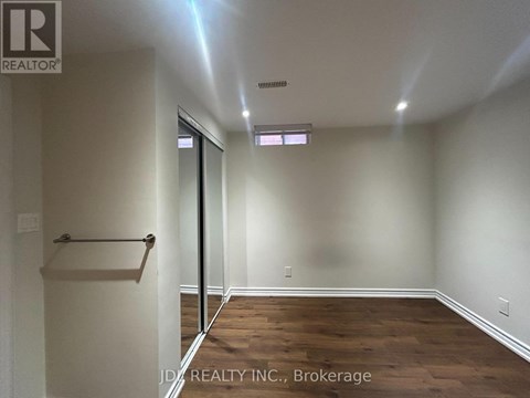 A room with wooden floors and white walls, with a door leading to another room.