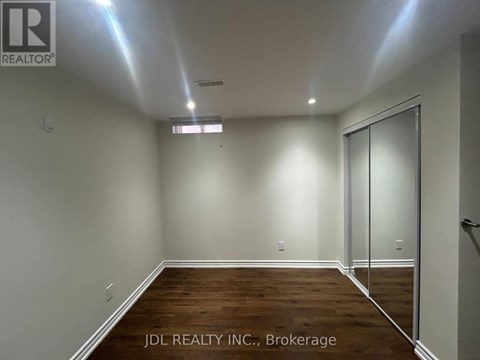 A room with wooden flooring and white walls, with a glass door on the right side.