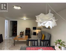 A living room with a couch, a coffee table, and a hanging light fixture.