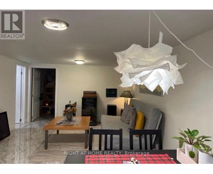 A living room with a couch, a coffee table, and a hanging light fixture.