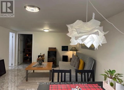 A living room with a couch, a coffee table, and a hanging light fixture.