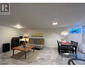 A living room with a grey couch, a coffee table, and a dining table with chairs.