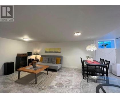 A living room with a grey couch, a coffee table, and a dining table with chairs.