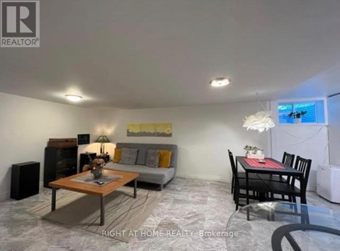 A living room with a grey couch, a coffee table, and a dining table with chairs.