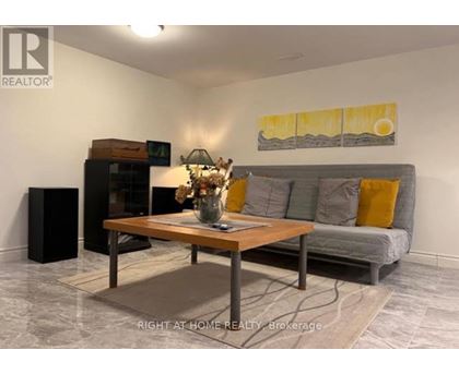 A living room with a grey couch, a wooden coffee table, and a painting on the wall.