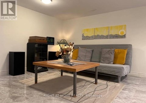 A living room with a grey couch, a wooden coffee table, and a painting on the wall.