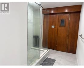 A bathroom with a glass shower stall and wooden doors.