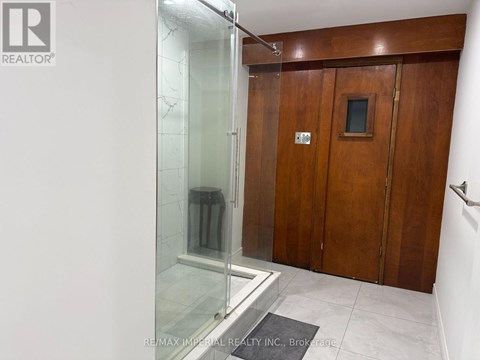 A bathroom with a glass shower stall and wooden doors.