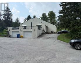 A white building with a garage door and a car parked in front.