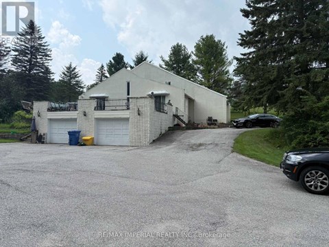 A white building with a garage door and a car parked in front.