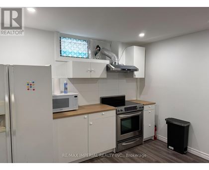 A kitchen with white cabinets and a black trash can.