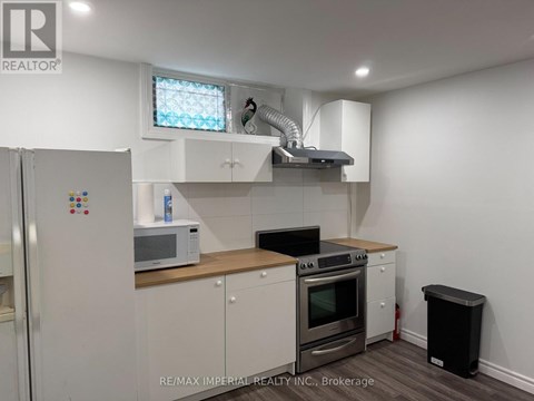 A kitchen with white cabinets and a black trash can.