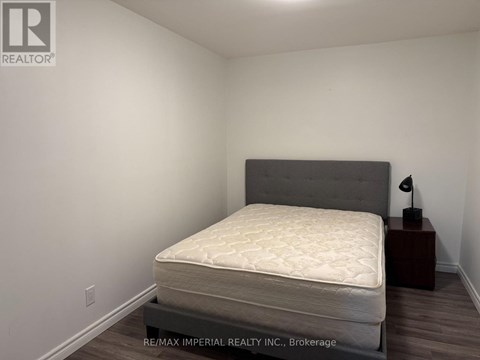 A bedroom with a bed, nightstand, and lamp.