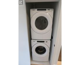 Two white Whirlpool washing machines in a cabinet.