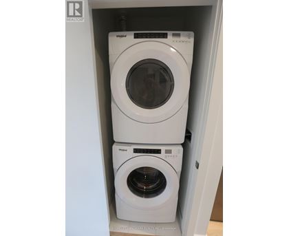 Two white Whirlpool washing machines in a cabinet.