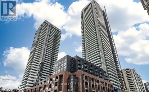 Two tall buildings stand behind a smaller building with a sign that says "REALTOR".