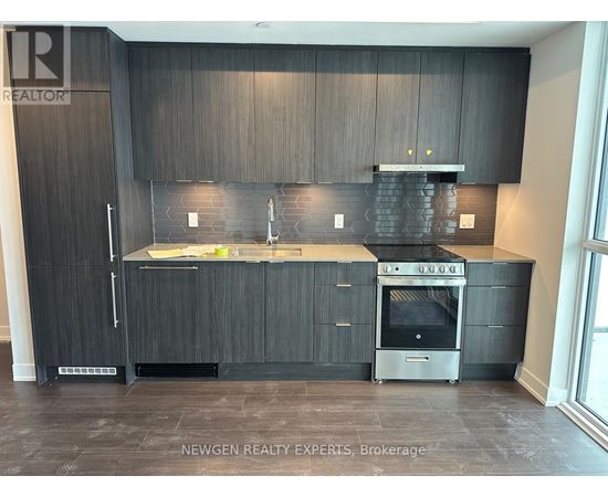 A modern kitchen with dark wood cabinets and stainless steel appliances.