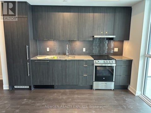 A modern kitchen with dark wood cabinets and stainless steel appliances.